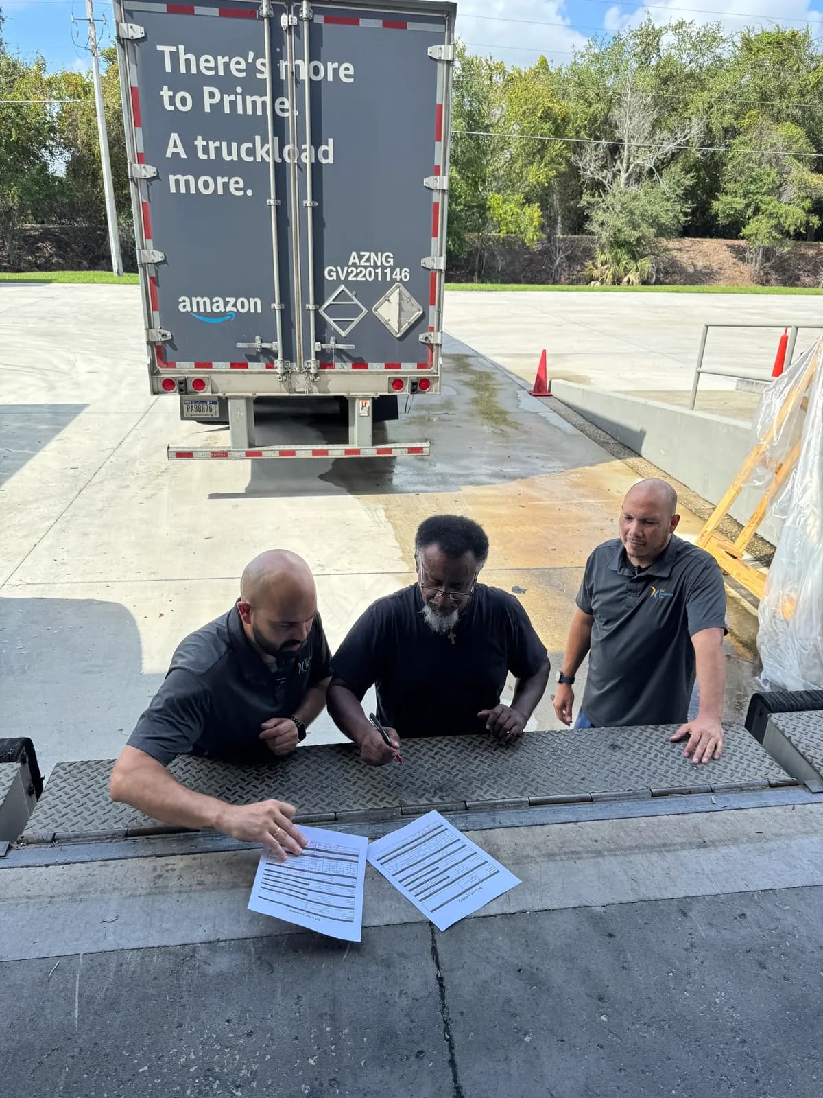 DC Logistics US staff signing a bill of lading at the dock beside an Amazon trailer